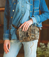 A woman wearing a denim jacket and jeans holding a Bed Stu Buffy purse.