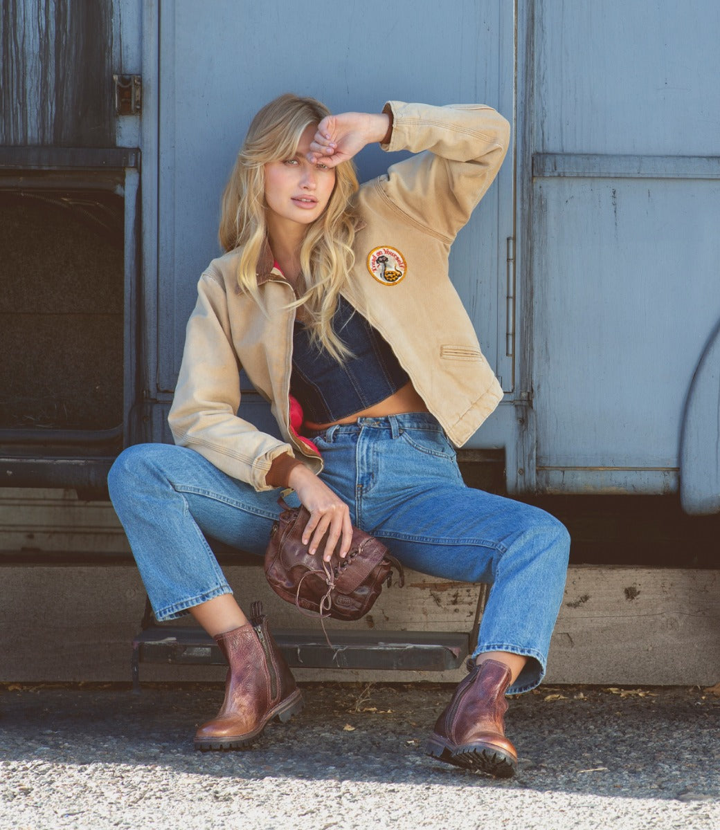 A blonde woman is sitting on the side of a Buffy truck by Bed Stu.