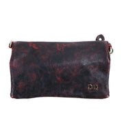 The Cadence clutch by Bed Stu is designed with black leather and a marbled red pattern, featuring a fold-over flap and metallic ring accents.