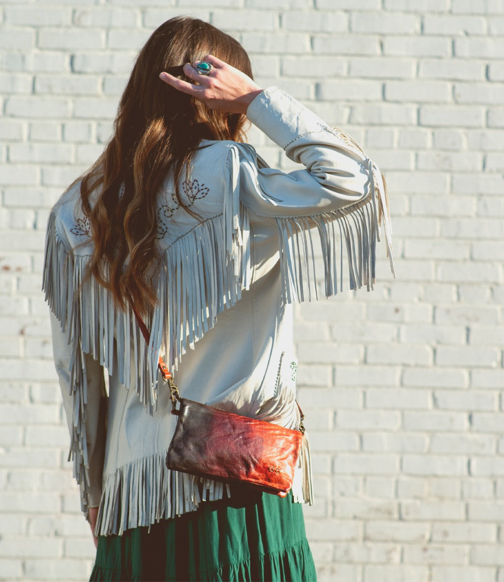 A woman wearing a Bed Stu Cadence multi-colored leather clutch.