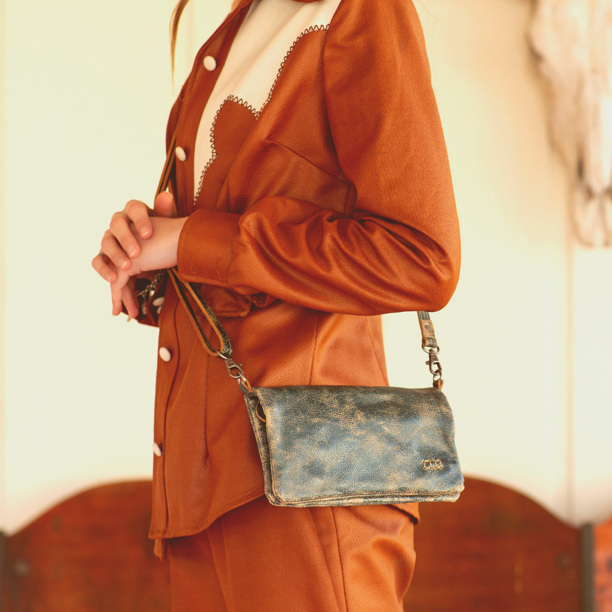 A woman wearing a Bed Stu Cadence brown leather clutch.