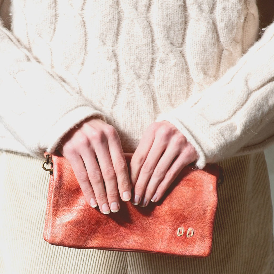 A woman holding a Bed Stu pink Cadence clutch.