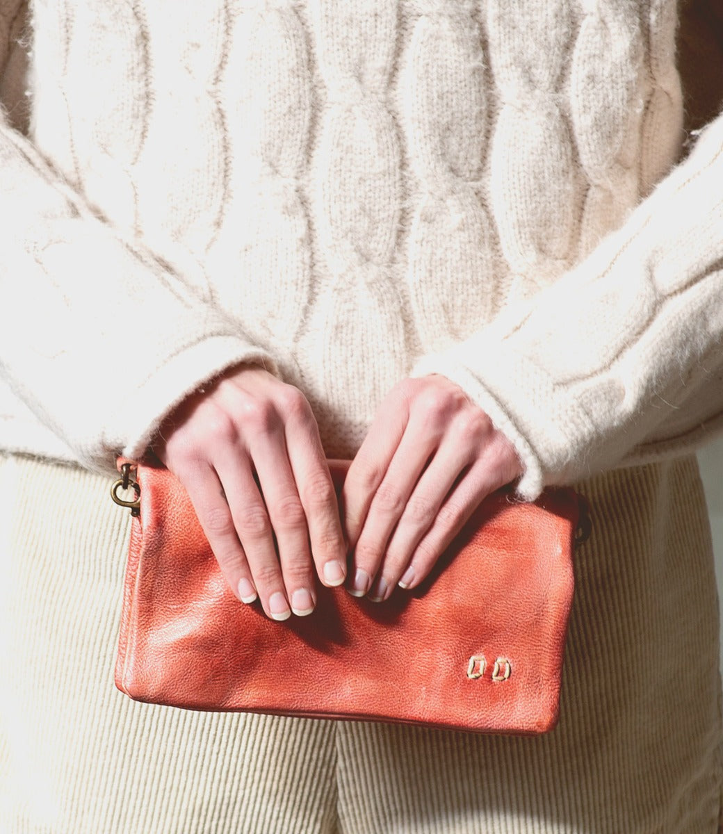 A woman holding a Bed Stu pink Cadence clutch.