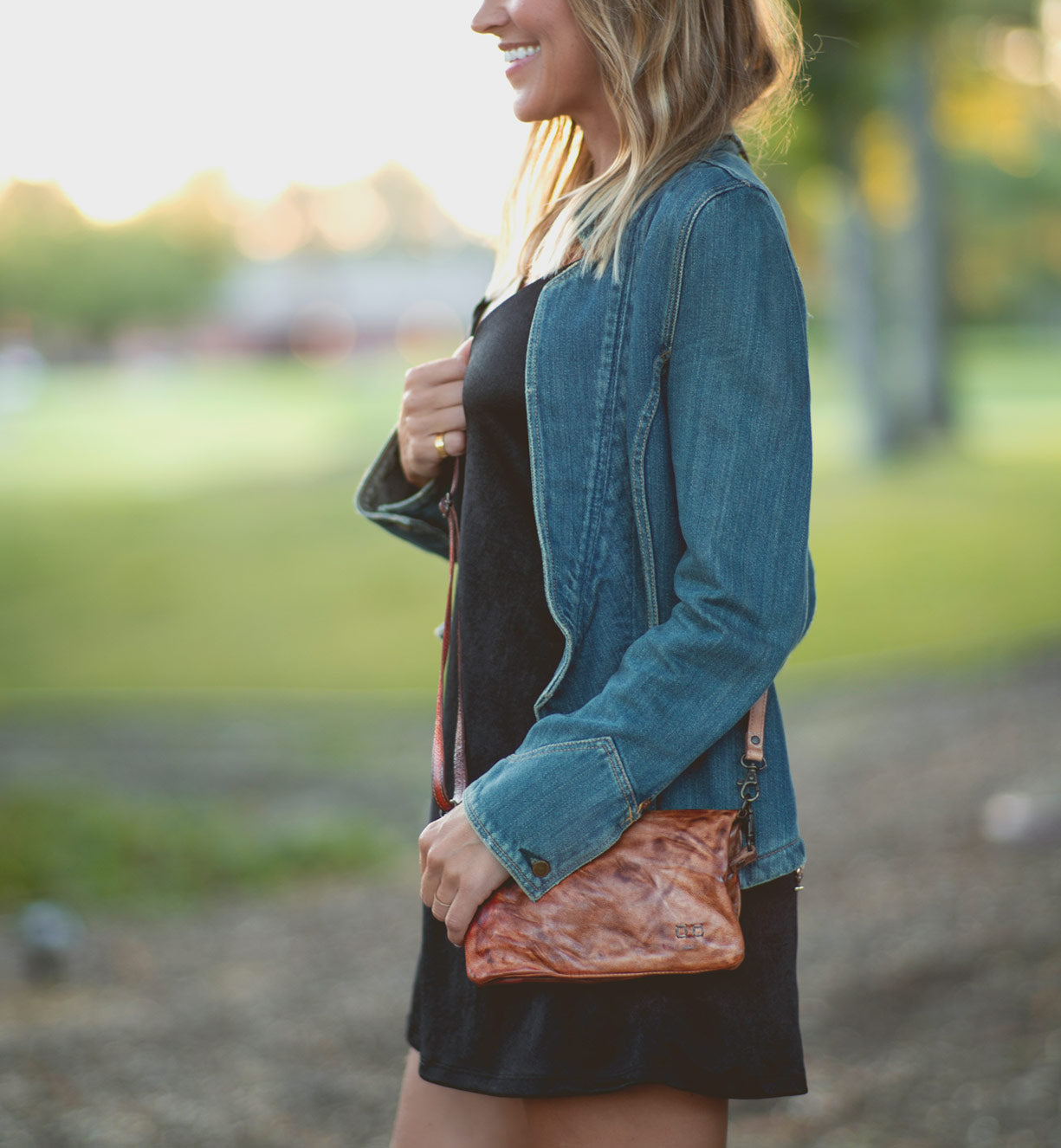 A woman wearing a denim jacket and a Bed Stu Cadence purse.
