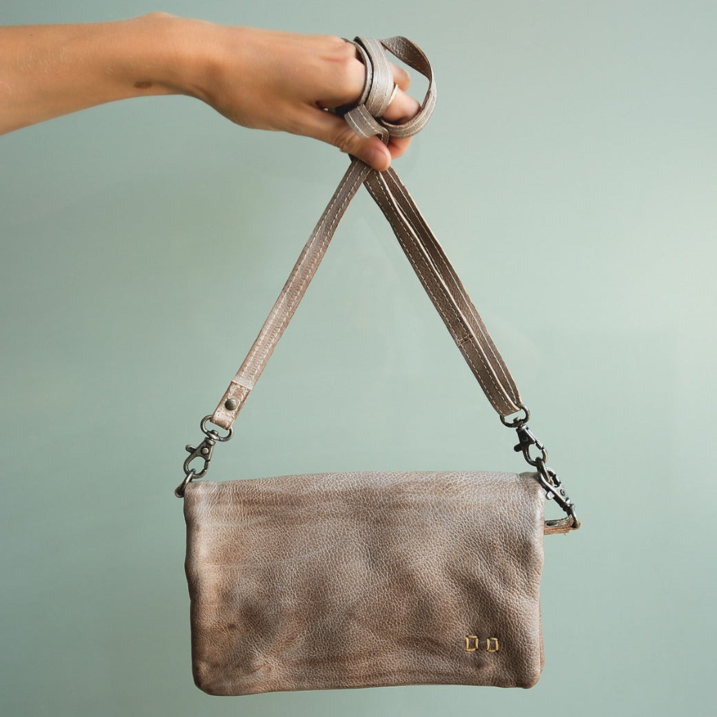 A hand holding a Cadence crossbody bag by Bed Stu.