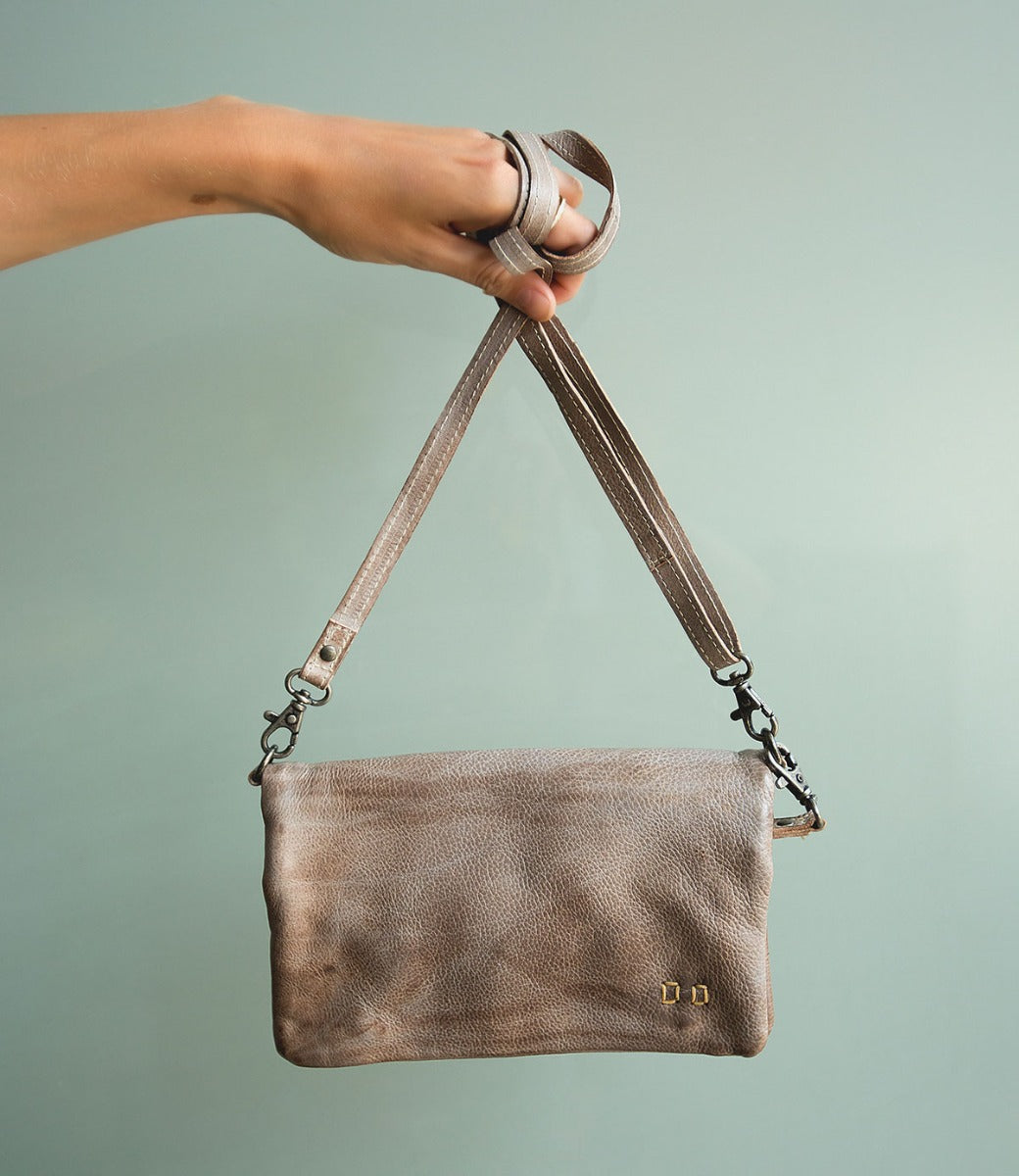 A hand holding a Cadence crossbody bag by Bed Stu.