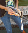 A woman wearing jeans and vest holding a Cadence clutch.