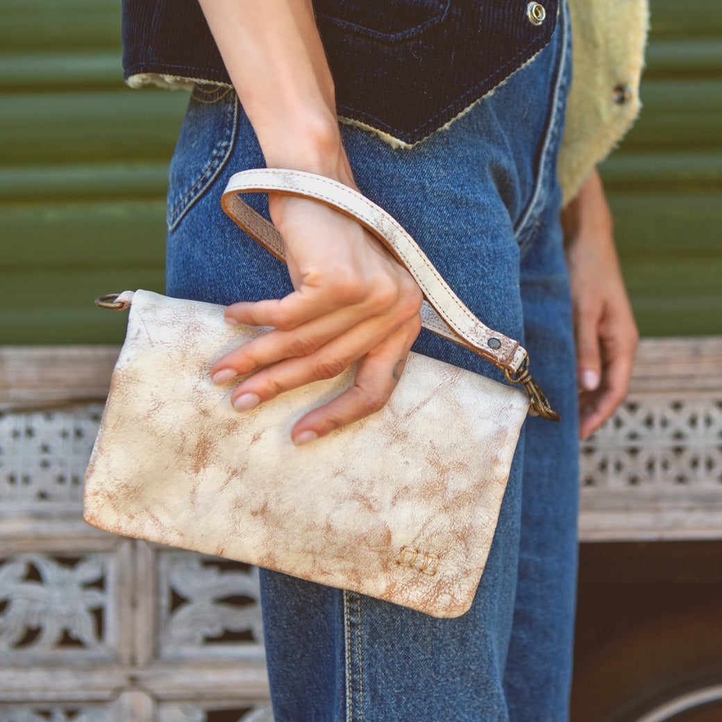 A woman holding a white Bed Stu Cadence clutch.