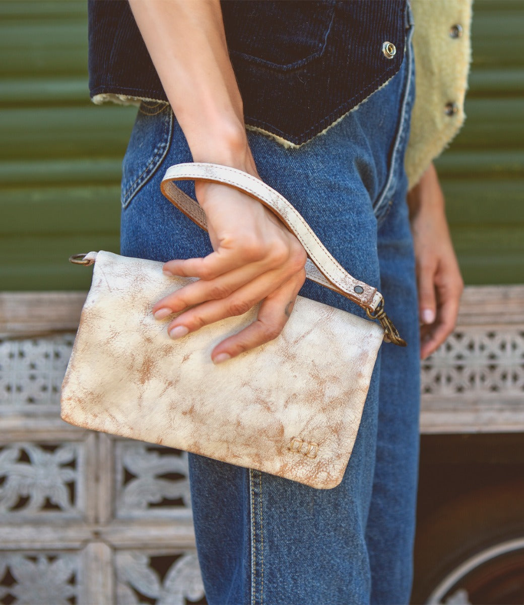 A woman holding a white Bed Stu Cadence clutch.