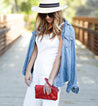 A woman wearing a white jumpsuit, hat and Bed Stu Cadence clutch.