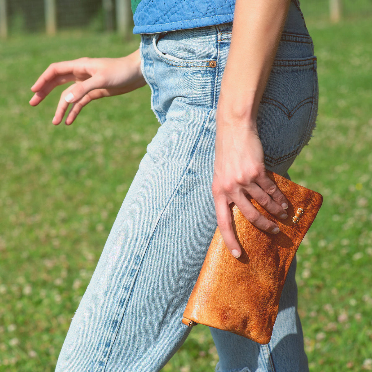 A woman wearing jeans and a Bed Stu Cadence leather clutch.