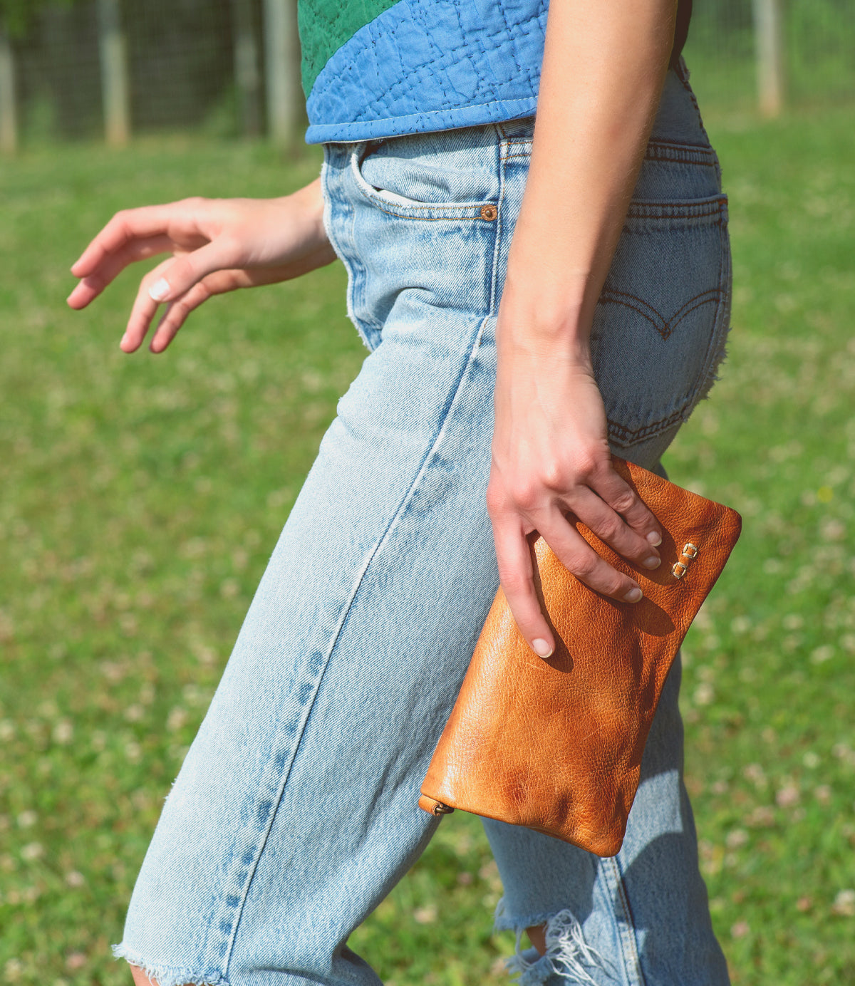 A woman wearing jeans and a Bed Stu Cadence leather clutch.