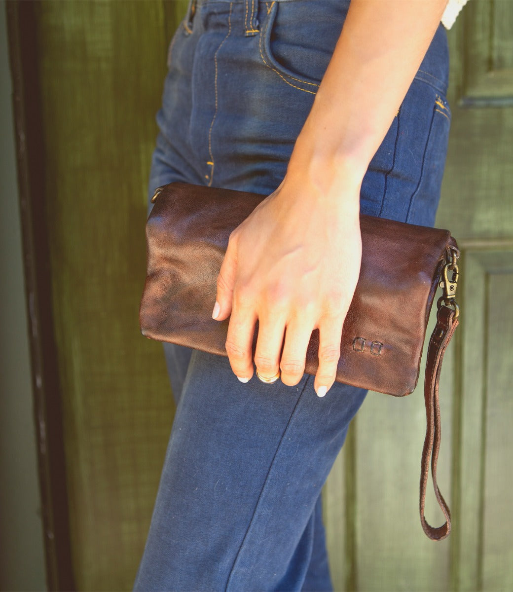 A woman holding a Cadence teak clutch from Bed Stu.