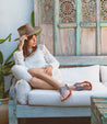 A woman wearing a pair of Bed Stu Callista leather sandals on a couch.