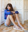 A woman sitting on a Camden rug with Bed Stu sandals on her feet.