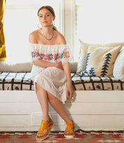 A young woman in a white dress sitting on a Bed Stu Camden couch.
