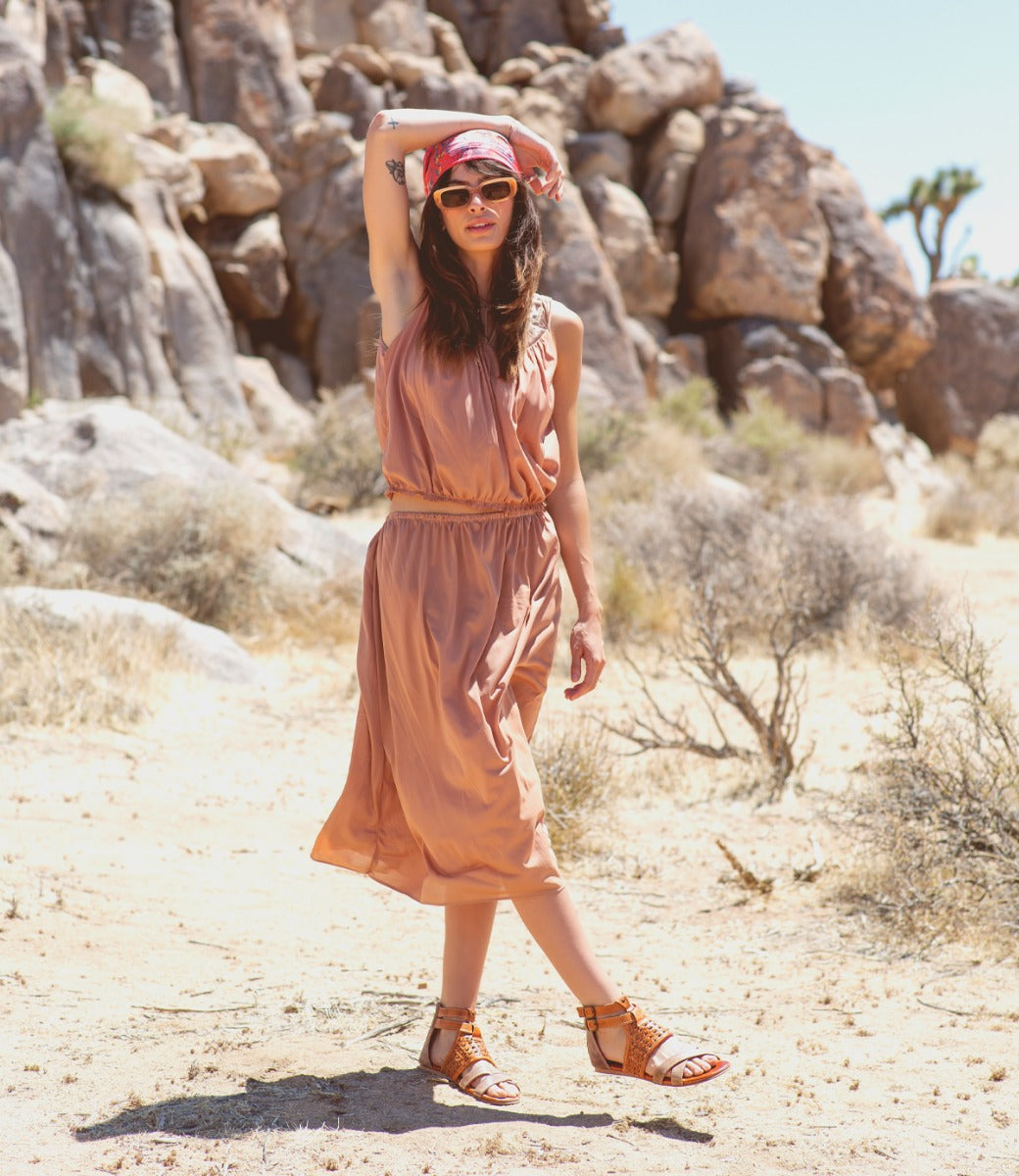 A woman in a tan dress standing in the desert wearing Capriana shoes by Bed Stu.