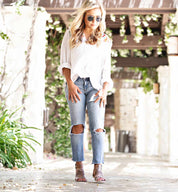 A blonde woman wearing Bed Stu ripped jeans and Capriana sandals.