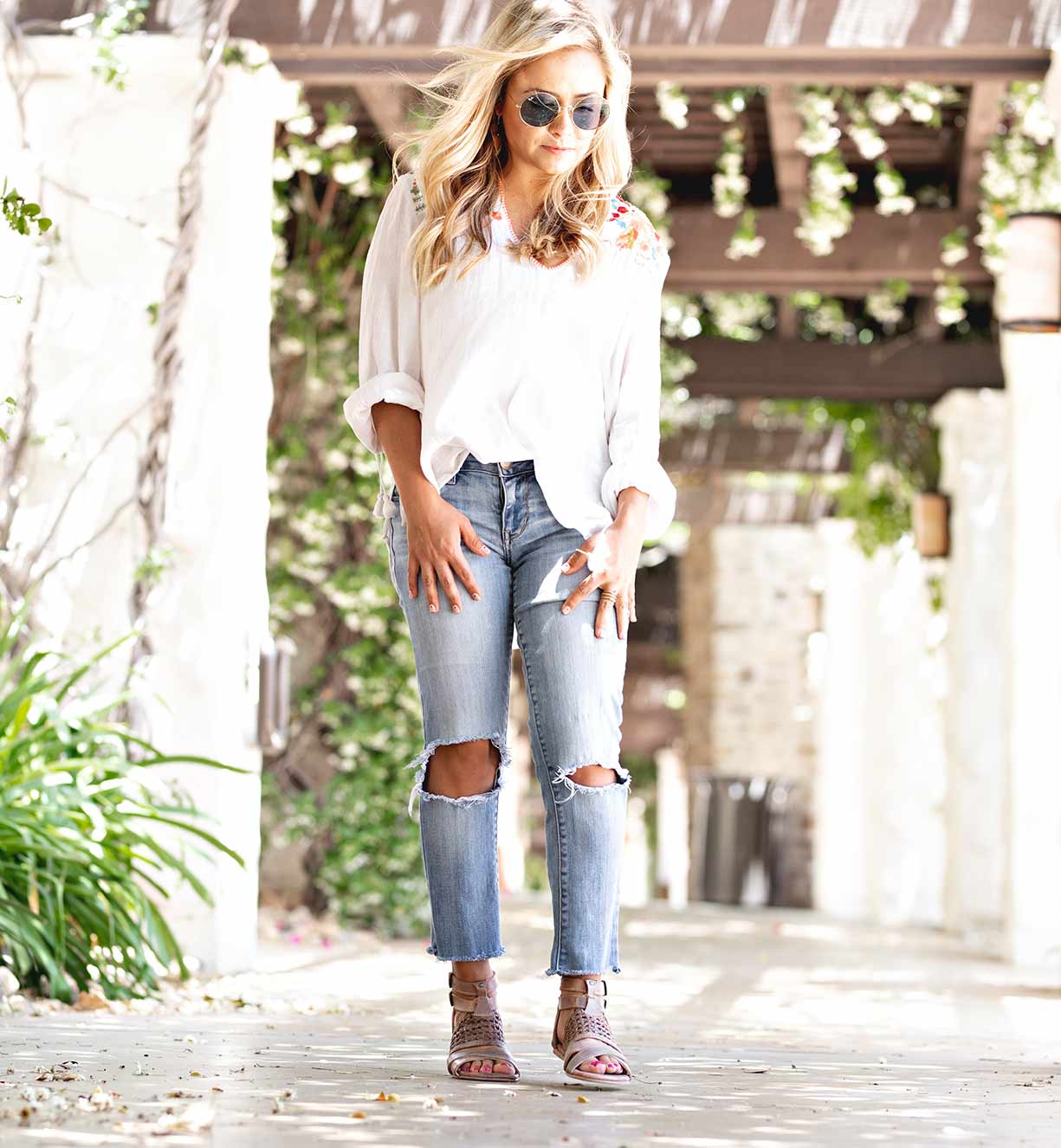 A blonde woman wearing Bed Stu ripped jeans and Capriana sandals.