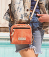 A woman is standing next to a pool holding a Bed Stu Capture bag.