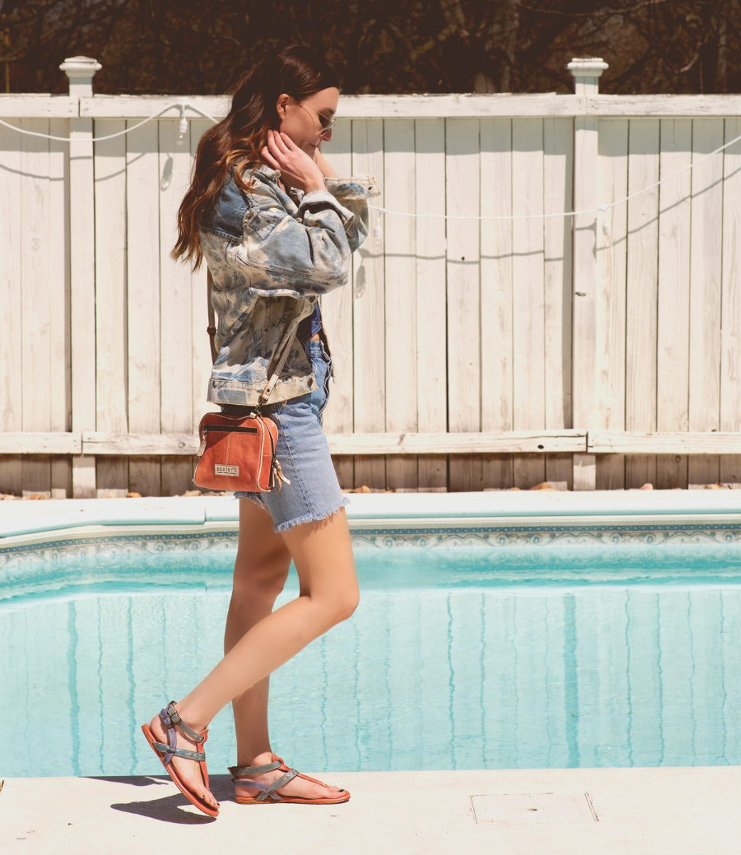 A woman standing by a pool wearing a denim jacket and Capture bag by Bed Stu.