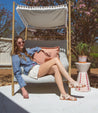 A woman is sitting on a Cara chair in a garden. (Brand: Bed Stu)