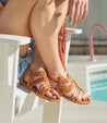 A woman is sitting on a white Cara chair next to a pool. (Brand: Bed Stu)