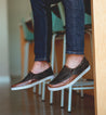 A person wearing a pair of Bed Stu Carp brown slip on shoes.