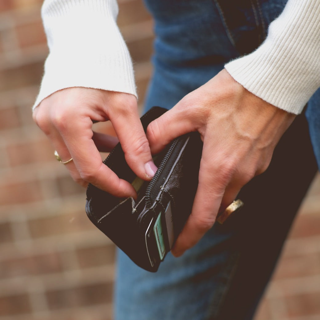 A woman is holding a black Bed Stu Carrie wallet in her hands.