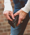 A woman is holding a black Bed Stu Carrie wallet in her hands.