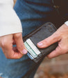 A person holding a Bed Stu Carrie wallet with a credit card in it.