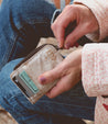 A woman is holding a Carrie wallet by Bed Stu with a credit card in it.