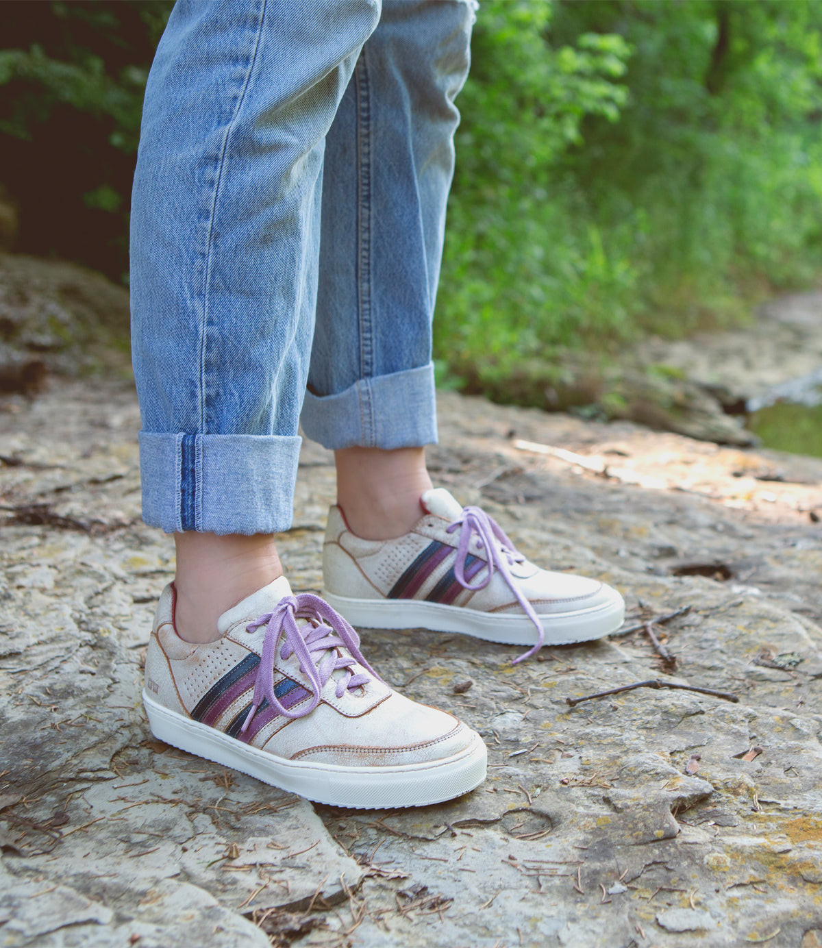 A woman wearing a pair of Bed Stu Carrington sneakers standing on a rock.