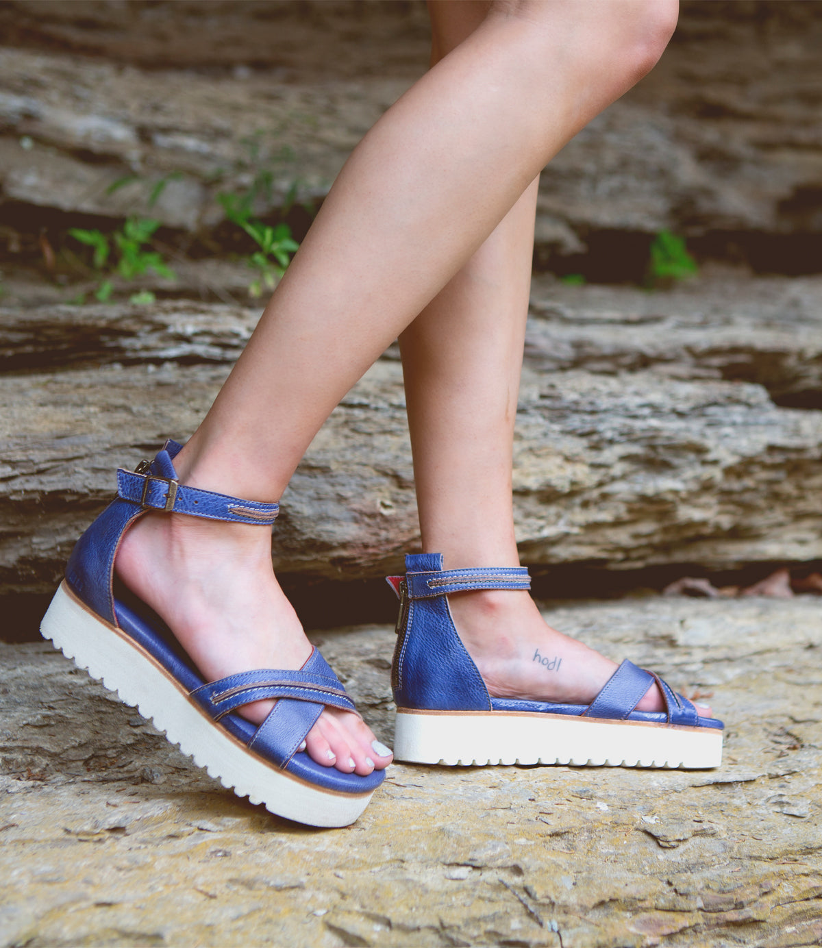 A woman wearing Bed Stu Carroll sandals standing on a rock.