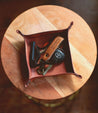 An Expanse leather key holder sitting on a wooden table. Brand: Bed Stu.