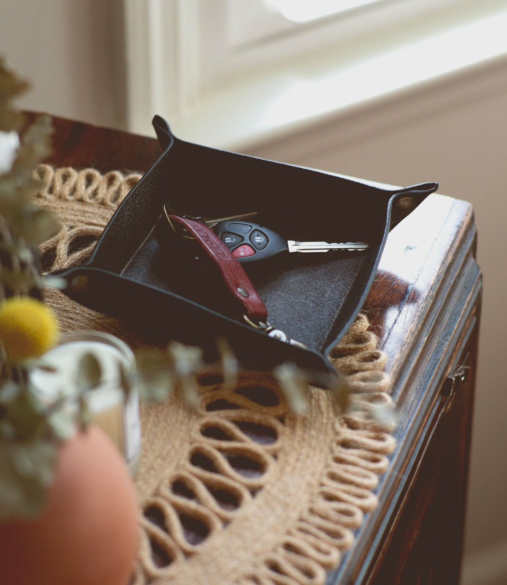 A black Expanse tray on a table next to a vase. (Brand: Bed Stu)