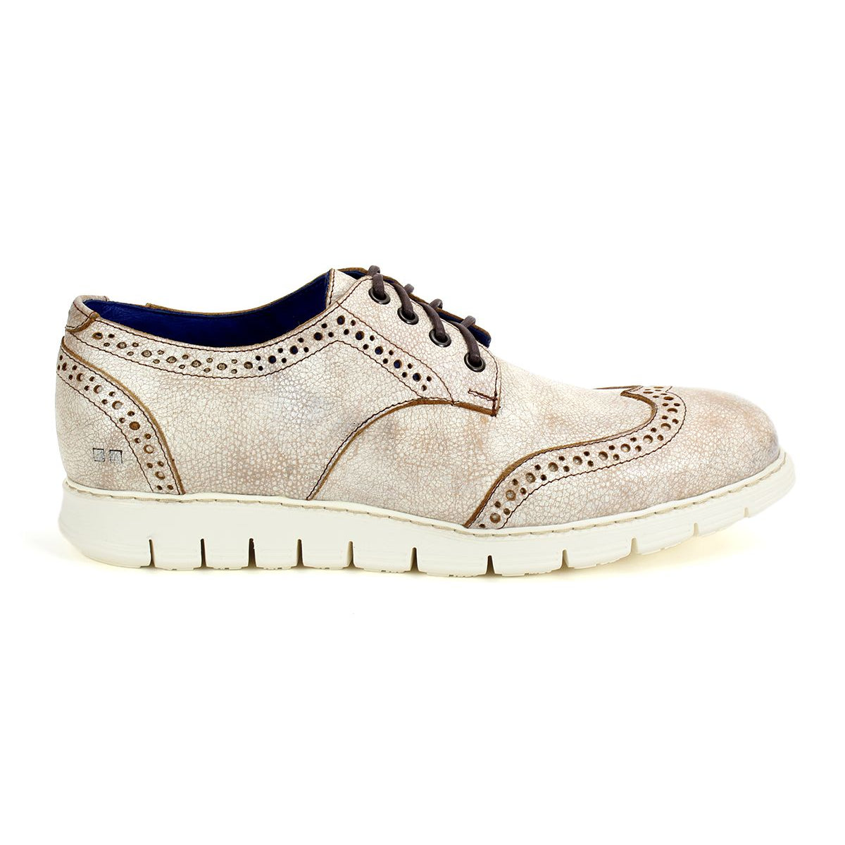 The Cayuga II by Bed Stu is a beige leather oxford shoe with stylish brogue details and decorative perforations, featuring a thick white rubber sole. This lightweight leather derby also has brown laces and a blue interior lining, encapsulating a contemporary casual male style.