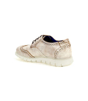 A single light brown Cayuga II brogue shoe by Bed Stu, featuring stylish brogue details and a white rubber sole, viewed from the side and slightly behind, isolated on a white background.