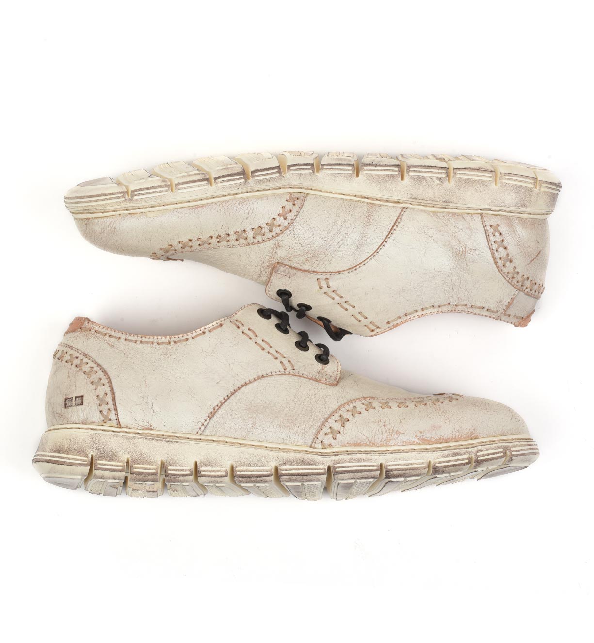 A pair of worn-out Bed Stu Cayuga II beige sneakers with black laces and brogue details on a white background.