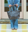 A woman in jeans holding a Bed Stu Celindra LTC tote bag.