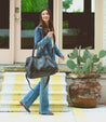 A woman wearing a denim jacket and carrying a Bed Stu Rockaway handbag.