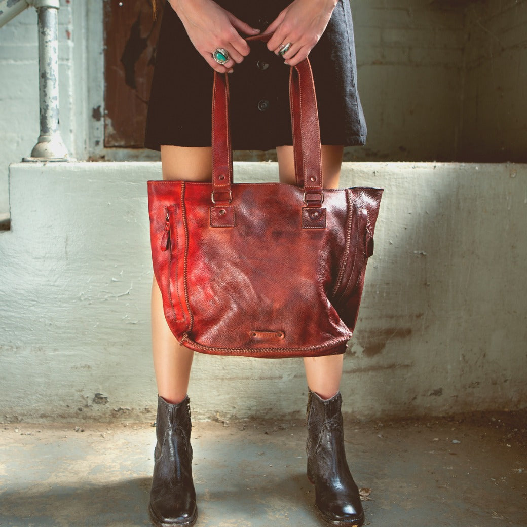 A woman holding a Celindra LTC red leather tote bag by Bed Stu.