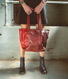 A woman holding a Celindra LTC red leather tote bag by Bed Stu.