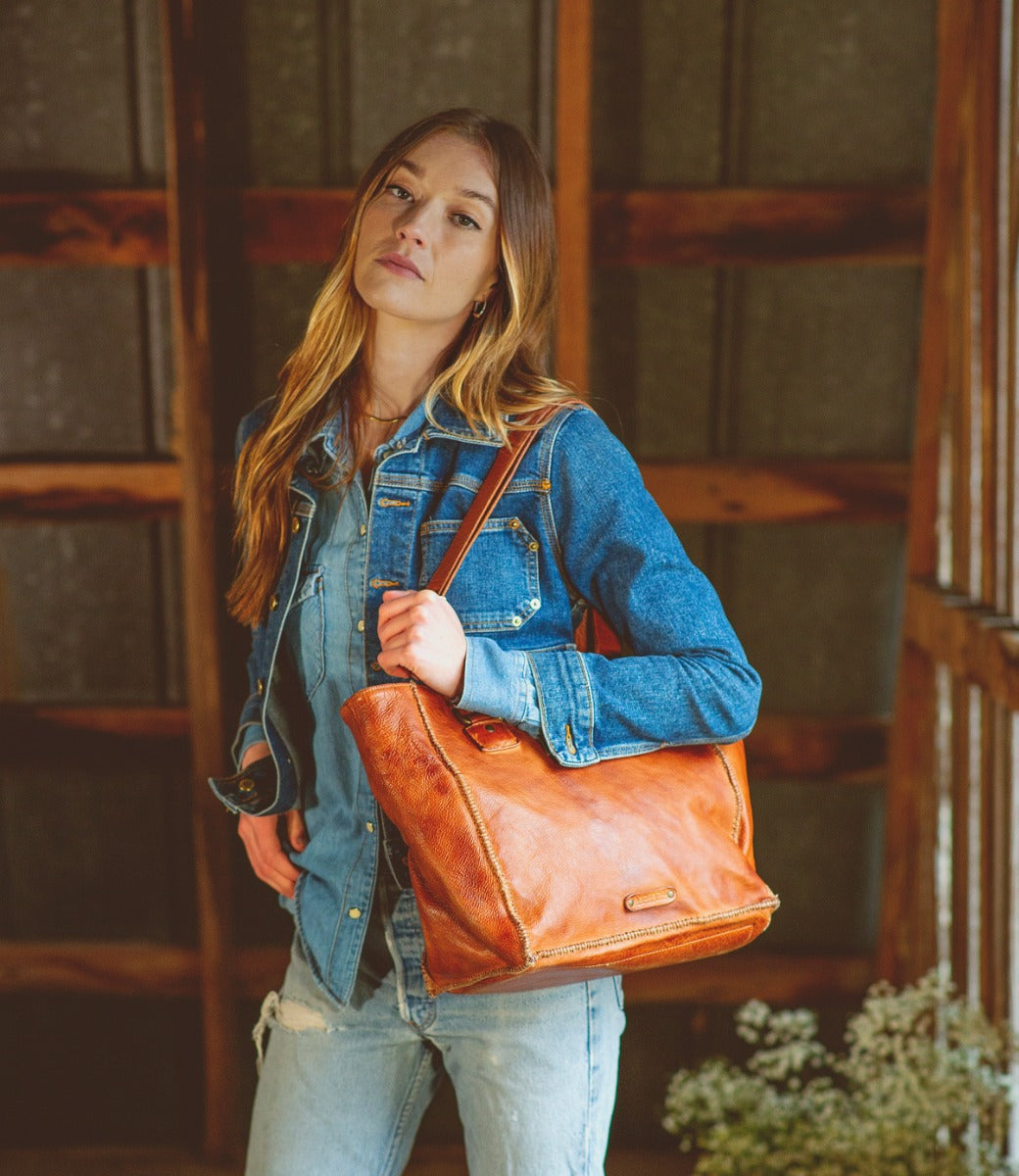 A woman wearing jeans and a denim jacket holding a Bed Stu Celindra LTC.