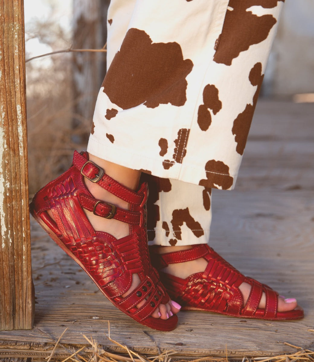 A woman wearing red Claire III sandals and Bed Stu cowboy pants.