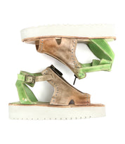 Two mismatched Bed Stu Clancy sandals with rugged soles are arranged vertically. One is brown, the other green, each featuring an ankle strap, zipper, and metal grommet details for flair.