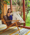 Woman sitting on a chair wearing Clancy white leather sandal with white sole by Bed Stu.