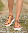 Woman wearing Clancy sandals by Bed Stu, made of tan leather with a white sole.