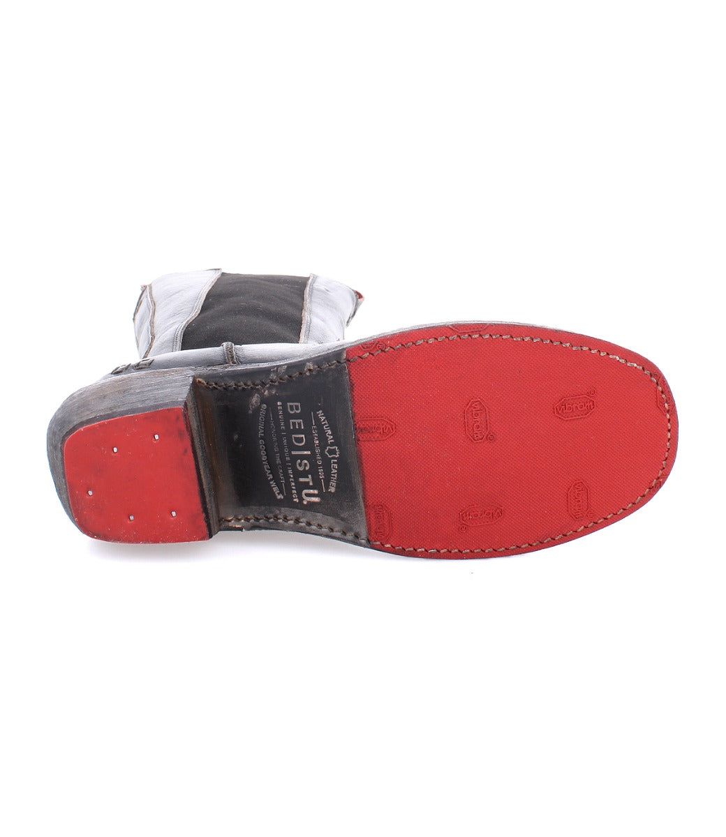 A pair of Clarisse boots with a red sole and a black sole by Bed Stu.