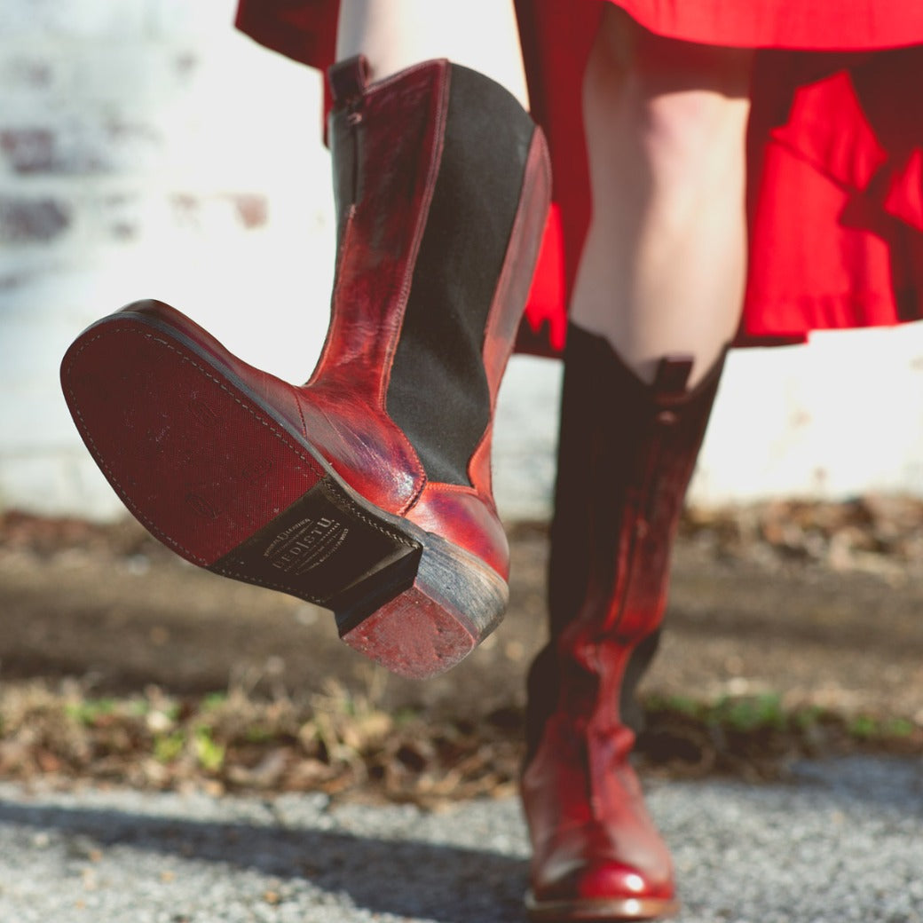 A woman wearing a red dress and Clarisse boots by  Bed Stu.